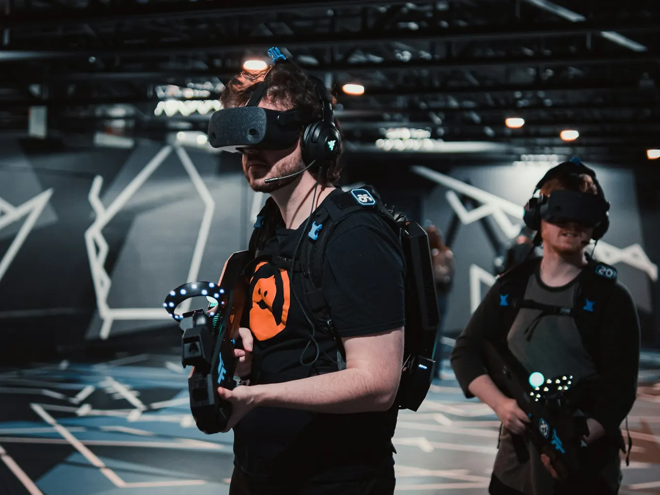 Participants wearing VR headsets and holding tracked controllers in a shared gaming space