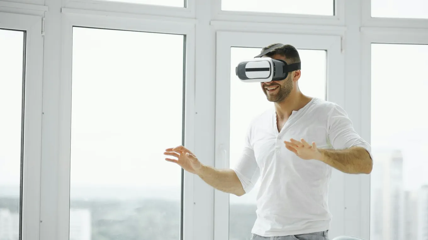 Person wearing a VR headset with hands raised in a bright room
