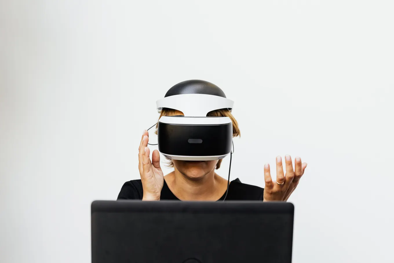 Woman wearing a headset and interacting with a virtual environment at a computer